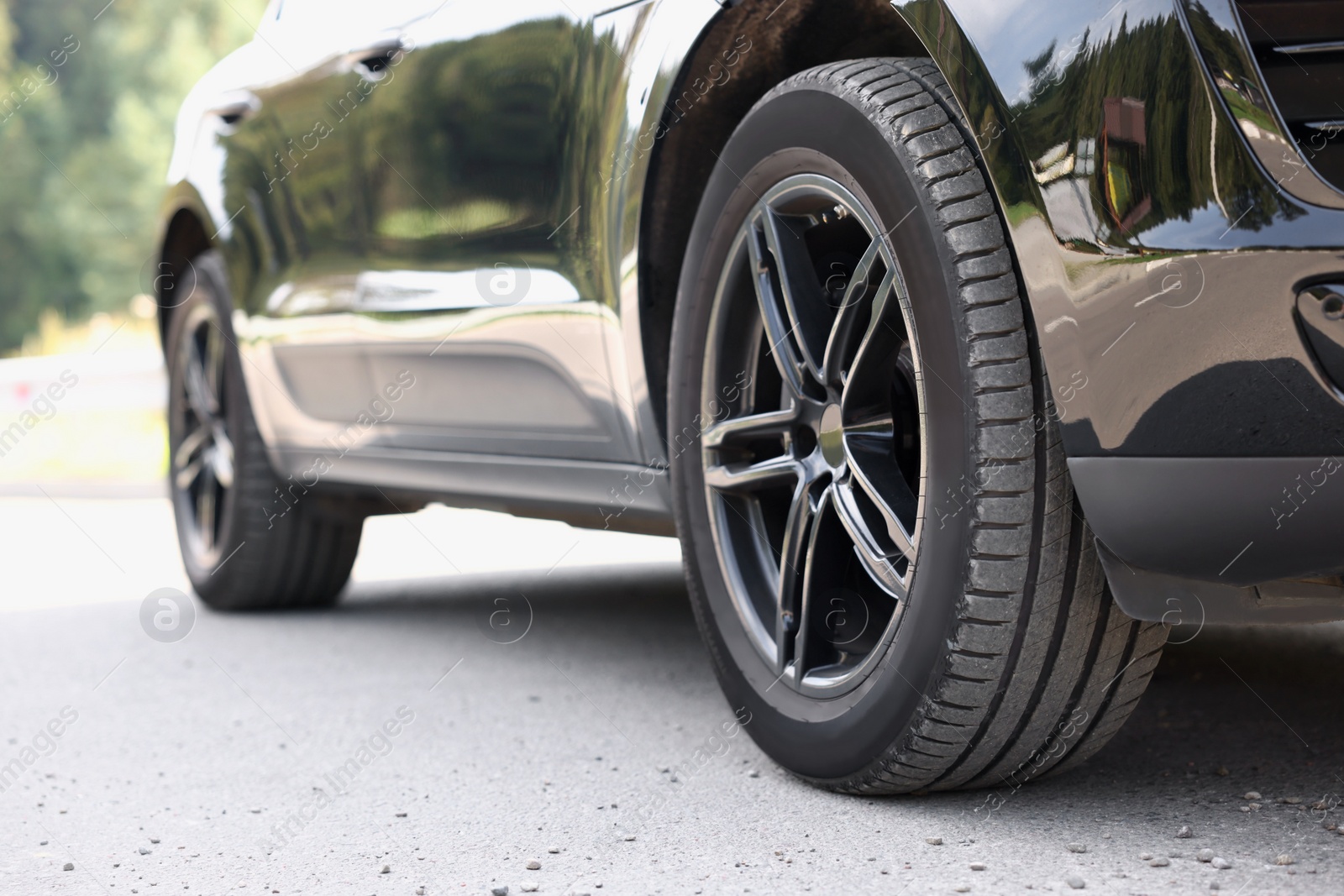 Photo of Modern black car parked on asphalt road outdoors, closeup