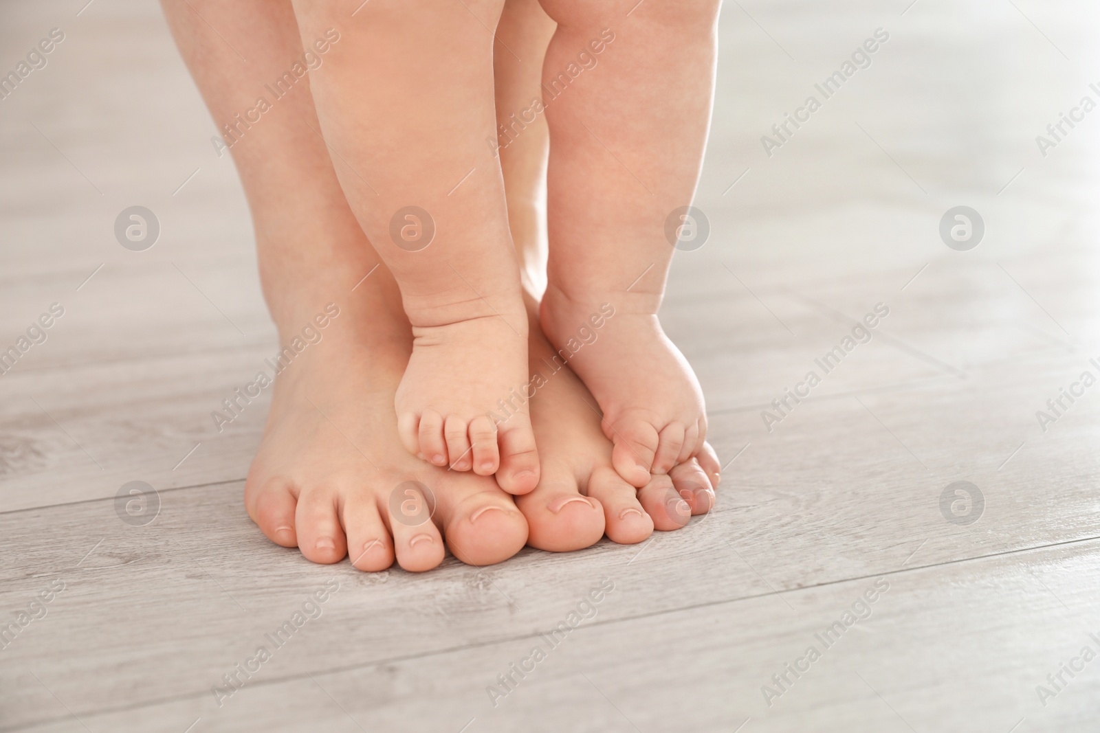 Photo of Mother and her baby standing on floor, closeup of legs