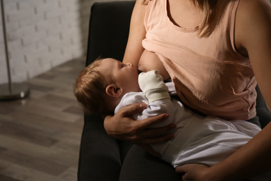 Photo of Young woman breast feeding her little baby at home, closeup