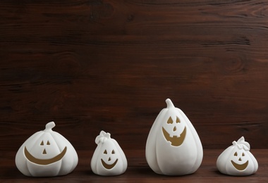 Jack-o-Lantern candle holders on table against wooden background, space for text. Halloween decor