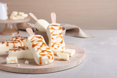 Photo of Delicious glazed ice cream bars and chocolate on light grey marble table