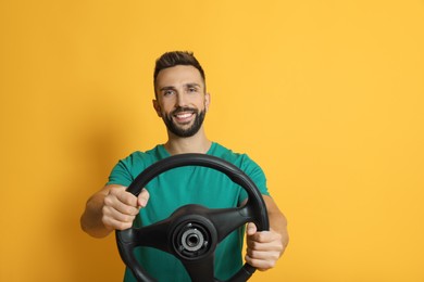 Photo of Happy man with steering wheel on yellow background