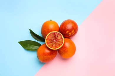 Ripe sicilian oranges and leaves on color background, flat lay