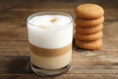 Photo of Delicious latte macchiato and cookies on wooden table