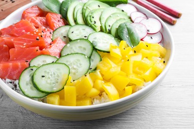 Photo of Delicious poke bowl with salmon and vegetables on wooden table, closeup