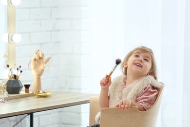 Cute little girl playing with cosmetics in dressing room