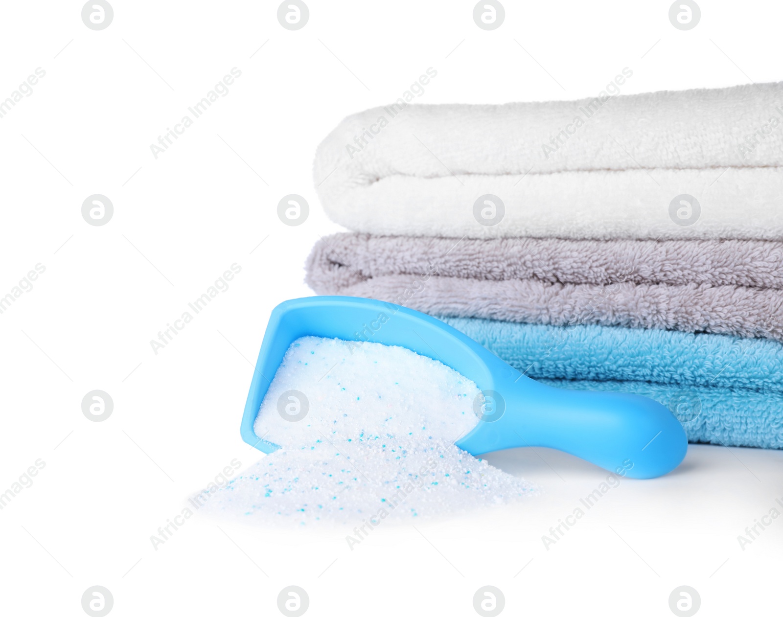 Photo of Laundry detergent in plastic measuring scoop and towels on white background