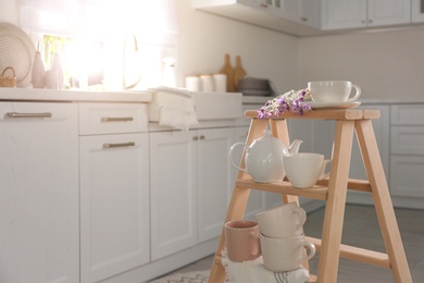 Decorative ladder with different dishware in kitchen. Idea for interior design