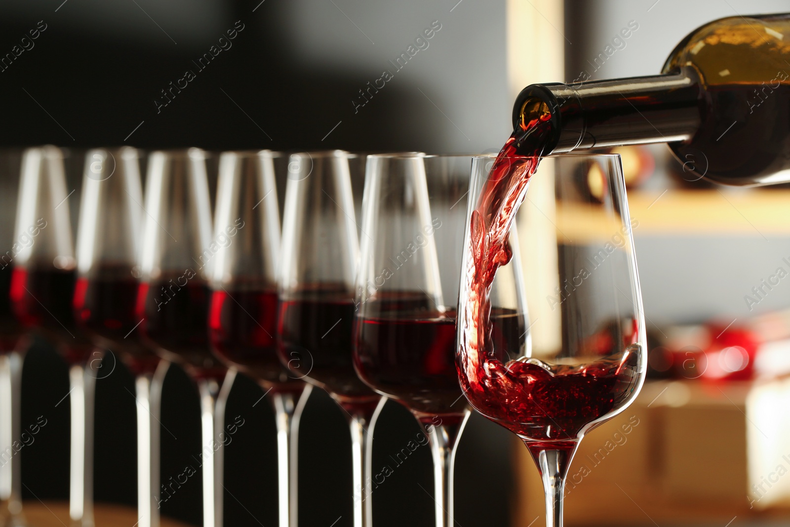 Photo of Pouring wine from bottle into glass in cellar, closeup