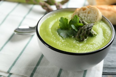 Photo of Delicious asparagus soup in bowl served on table