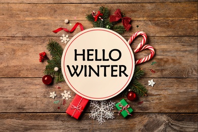 Image of Card with text Hello Winter, gift boxes and Christmas decor on wooden background, flat lay