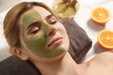 Photo of Beautiful woman with mask on face relaxing in spa salon, closeup
