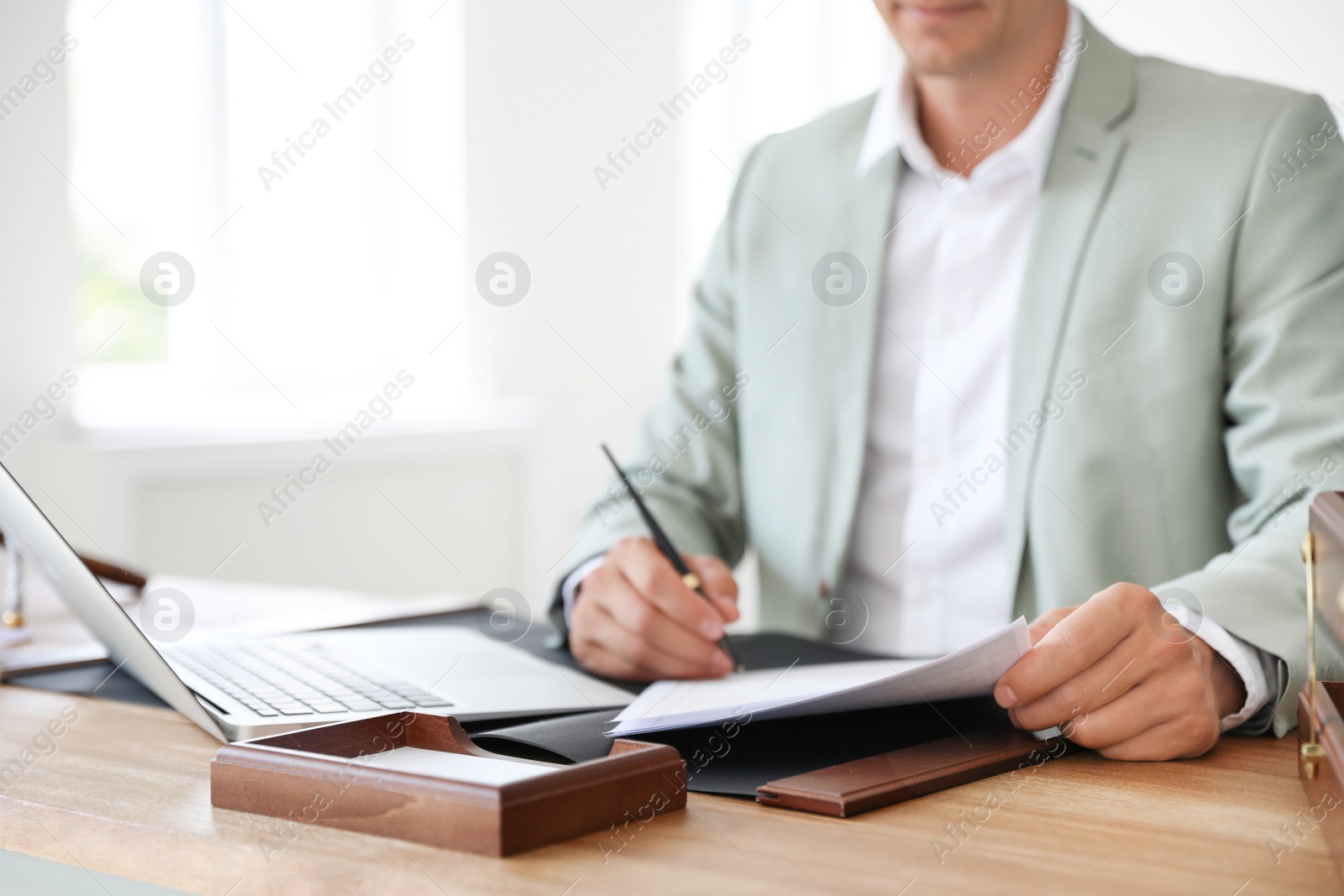 Photo of Male notary signing document at table in office, closeup