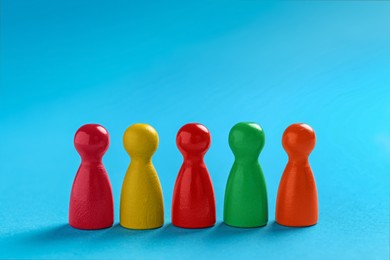 Photo of Colorful pawns on light blue background, closeup. Social inclusion concept