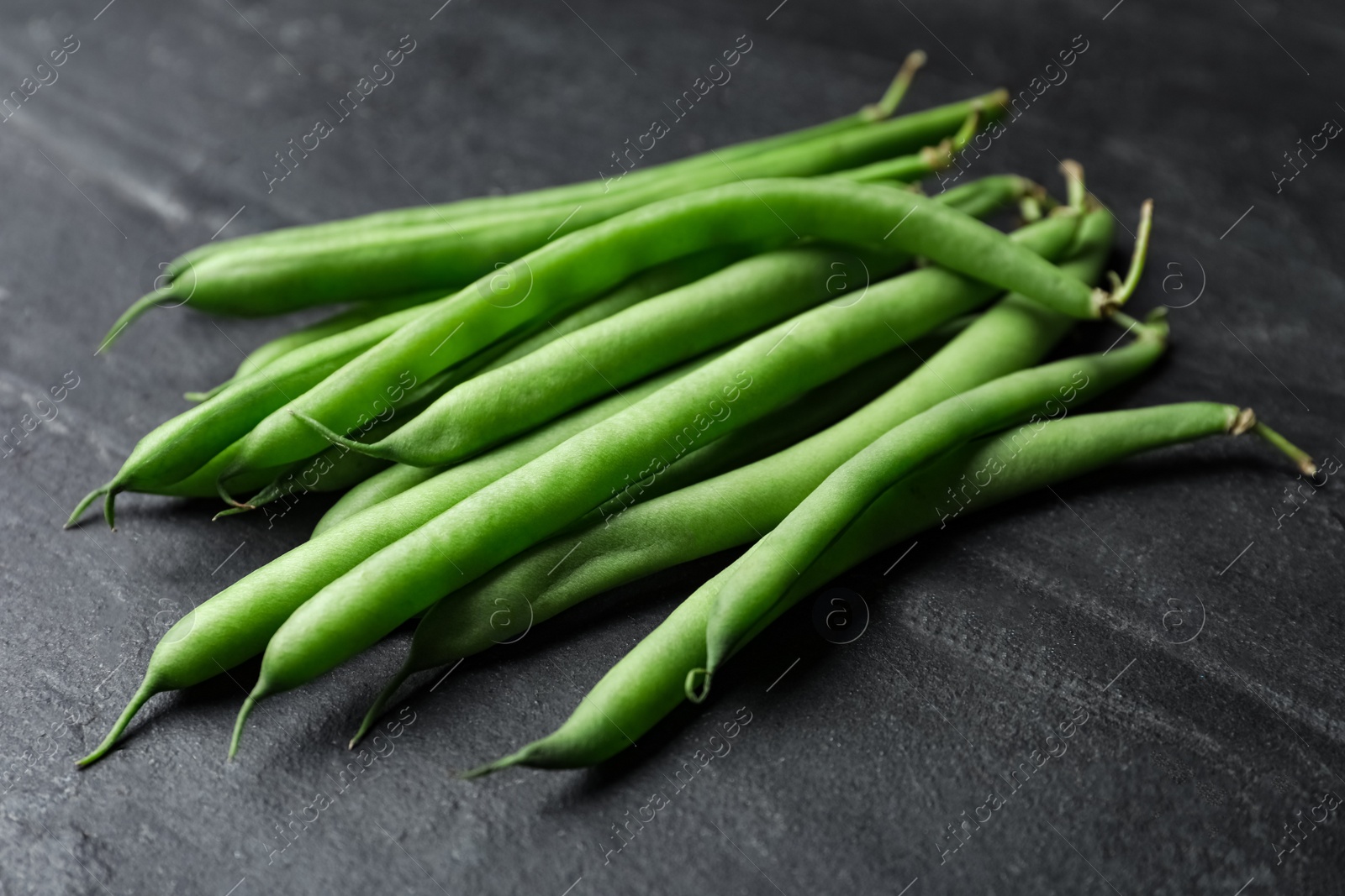 Photo of Fresh green beans on black table, closeup