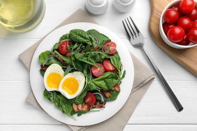 Photo of Delicious salad with boiled egg, bacon and tomatoes served on white wooden table, flat lay