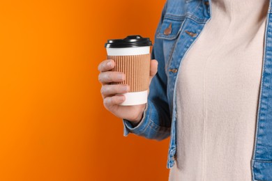 Photo of Woman holding takeaway cup with drink on orange background, closeup view and space for text. Coffee to go