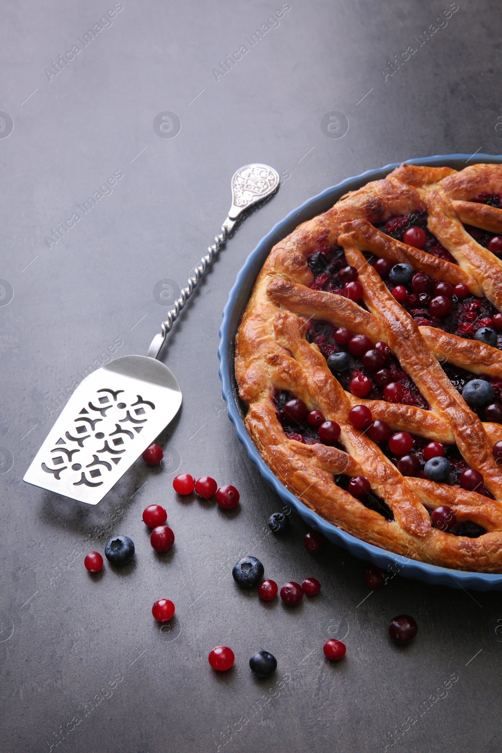 Photo of Delicious currant pie with fresh berries and spatula on grey table
