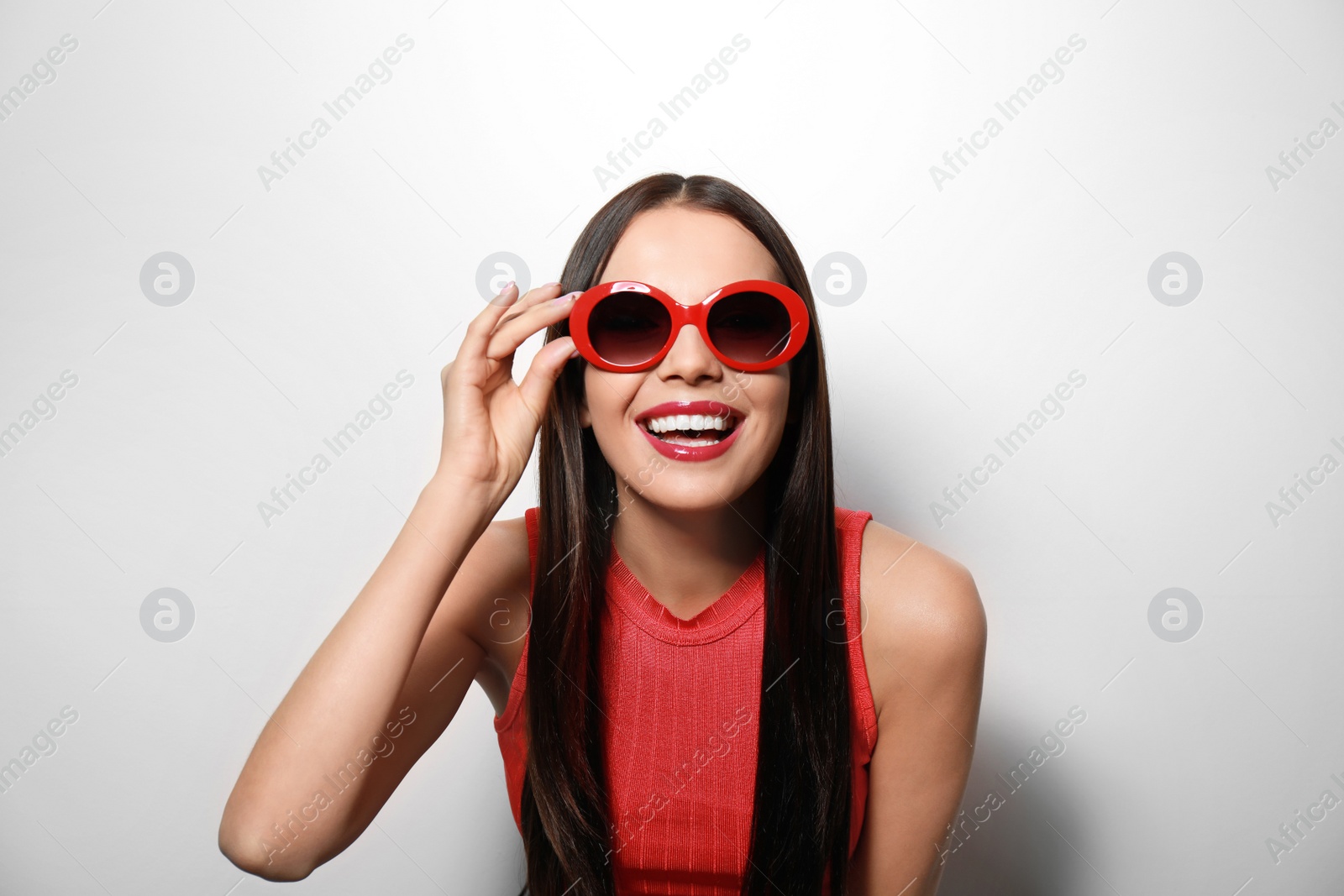 Photo of Beautiful woman in stylish sunglasses on light background