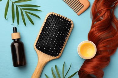 Photo of Flat lay composition with hair brush and comb on light blue wooden table