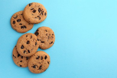 Photo of Many delicious chocolate chip cookies on light blue background, flat lay. Space for text