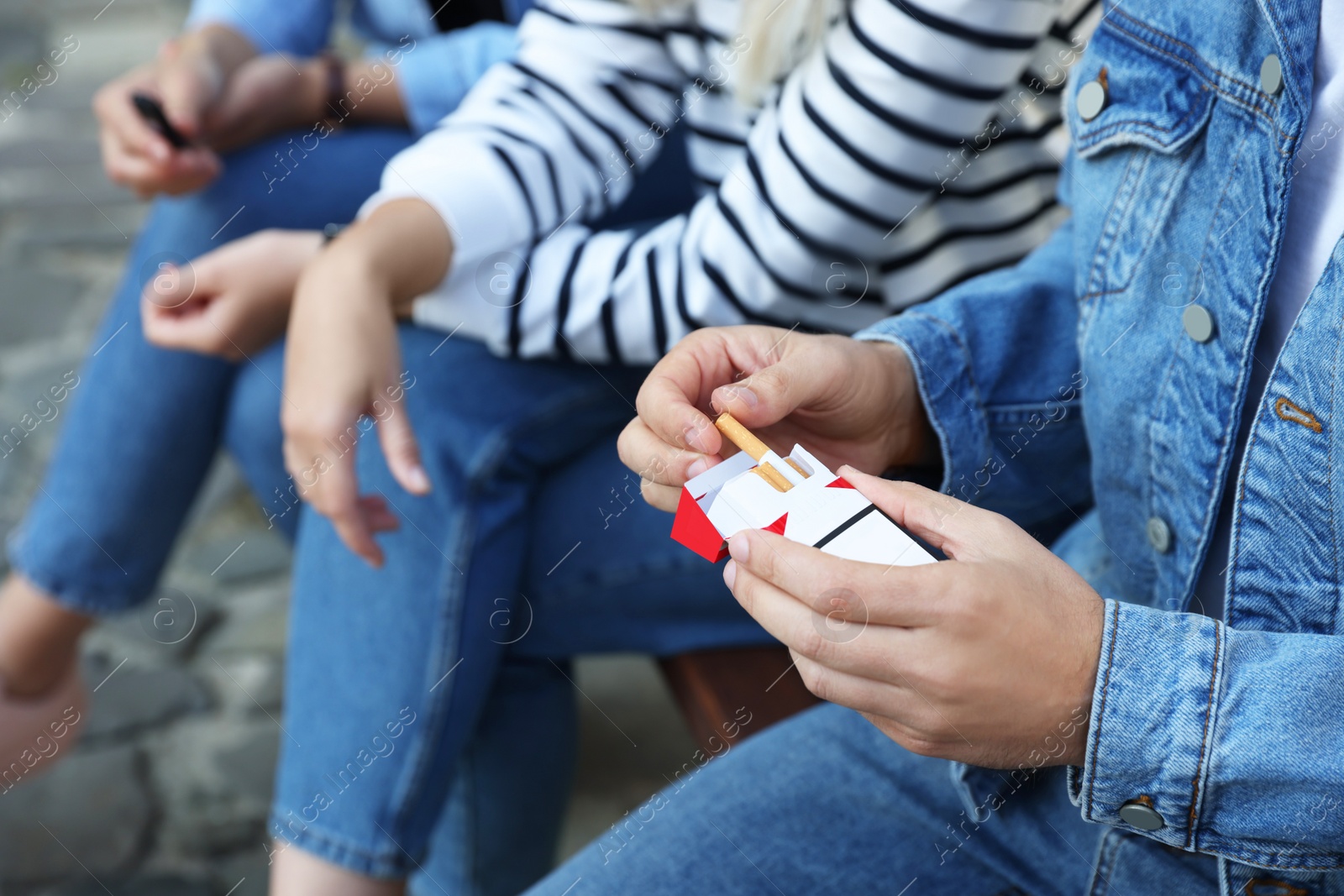 Photo of Man taking cigarette out of pack outdoors, closeup