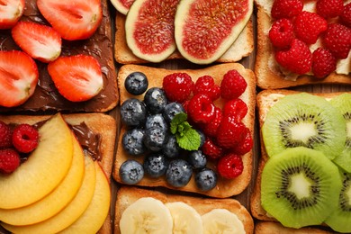 Tasty toasts with different spreads and fruits on wooden table, flat lay