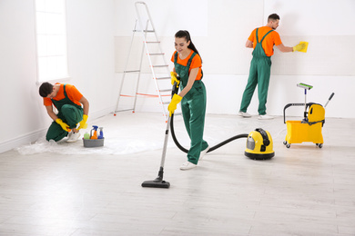 Team of professional janitors cleaning room after renovation