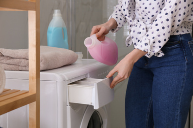 Photo of Woman pouring detergent into washing machine drawer in bathroom, closeup. Laundry day