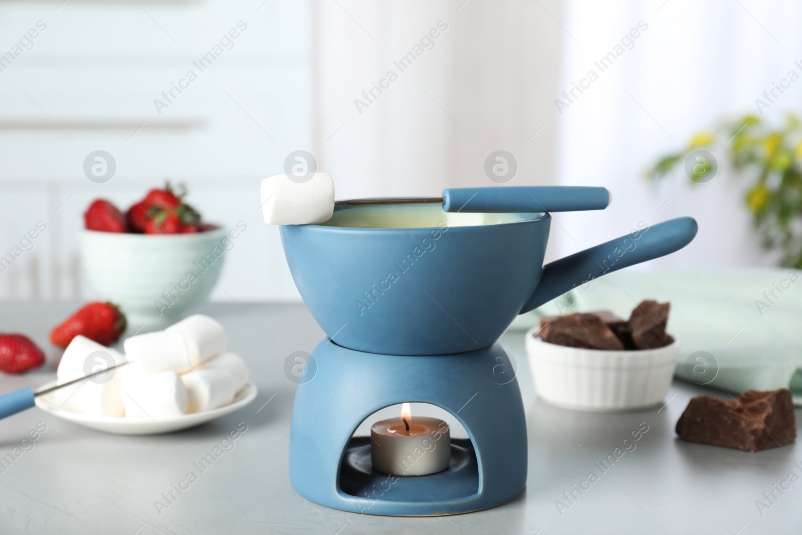 Photo of Ceramic pot with white chocolate fondue and marshmallow on table