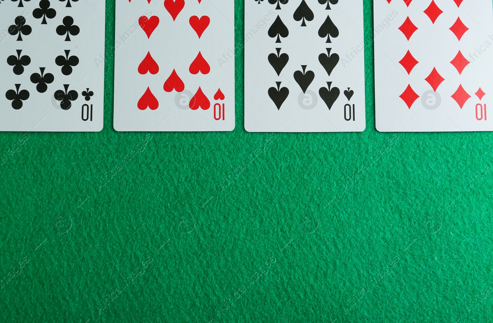 Photo of Playing cards with four of kind combination on green table, flat lay. Space for text