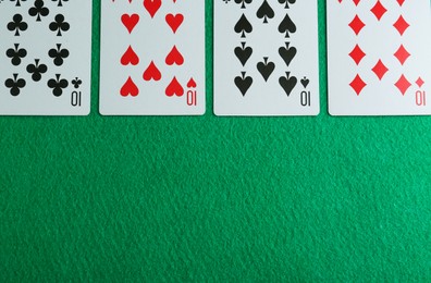Photo of Playing cards with four of kind combination on green table, flat lay. Space for text
