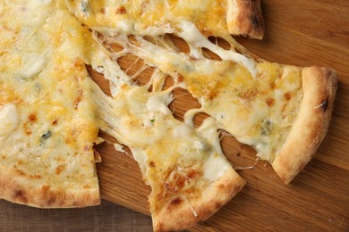 Photo of Delicious cut cheese pizza on wooden table, top view