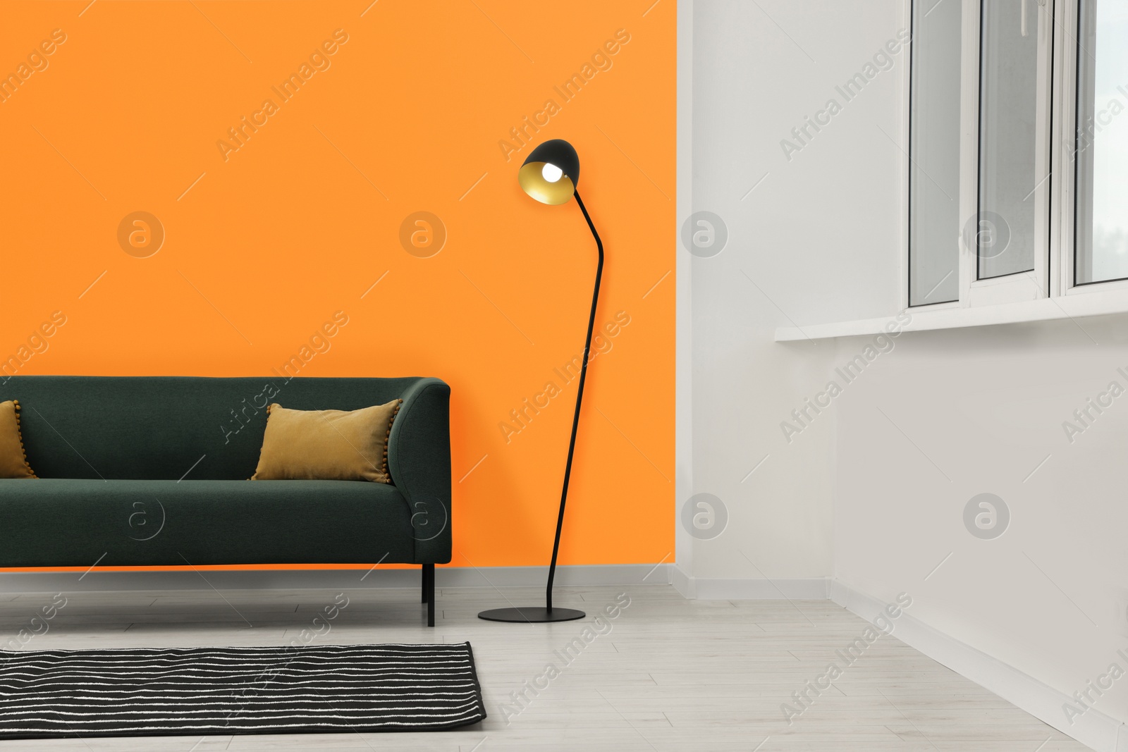 Photo of Beautiful interior with sofa and floor lamp near orange wall