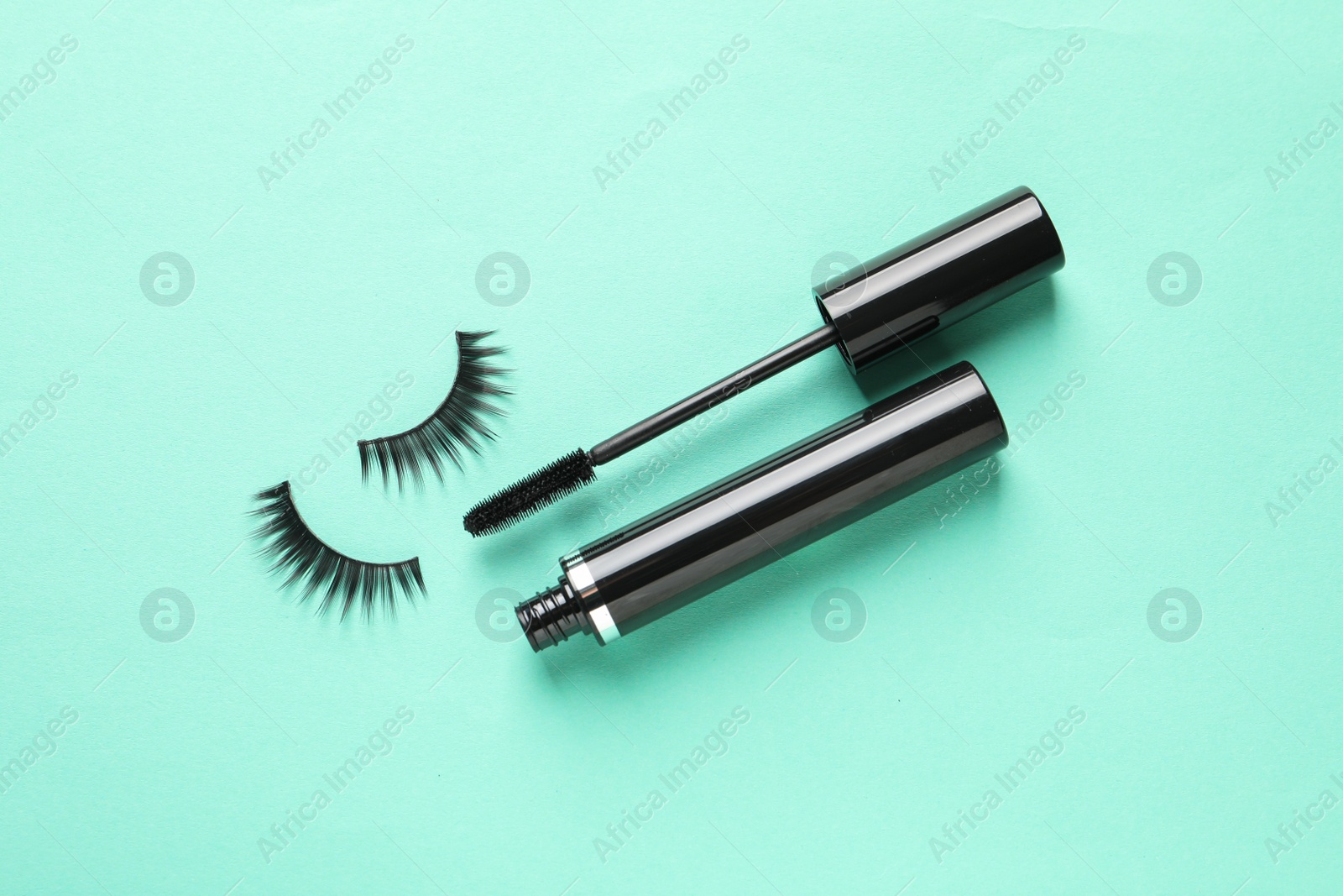 Photo of False eyelashes and mascara on turquoise background, flat lay