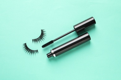 False eyelashes and mascara on turquoise background, flat lay