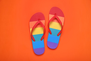 Photo of Rainbow flip flops on orange background, flat lay. LGBT pride