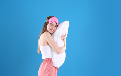 Photo of Young woman with pillow and sleep mask on blue background