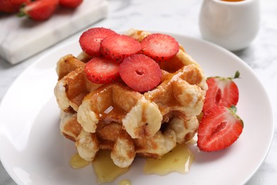 Photo of Delicious Belgian waffles with strawberries and honey on table, closeup