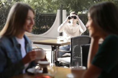 Man spying on his girlfriend in outdoor cafe. Cheating concept