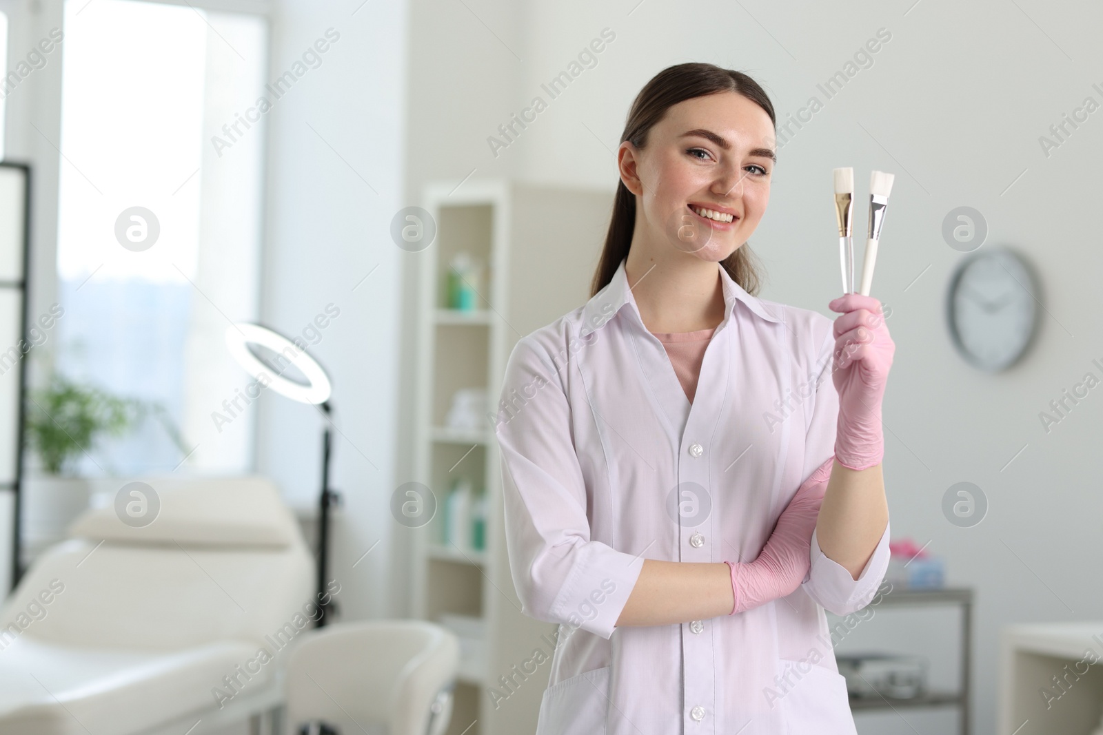 Photo of Cosmetologist with cosmetic brushes in clinic, space for text