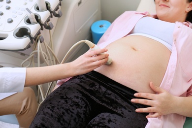 Pregnant woman undergoing ultrasound scan in clinic, closeup