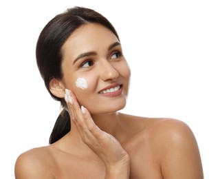 Photo of Young woman applying facial cream on white background