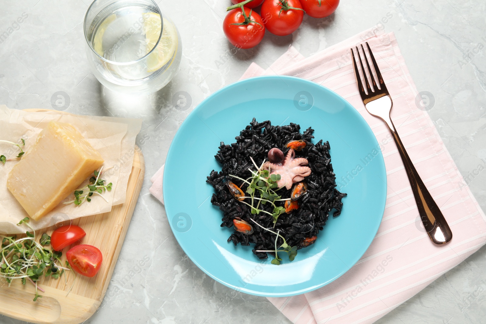 Photo of Delicious black risotto with seafood served on marble table, flat lay