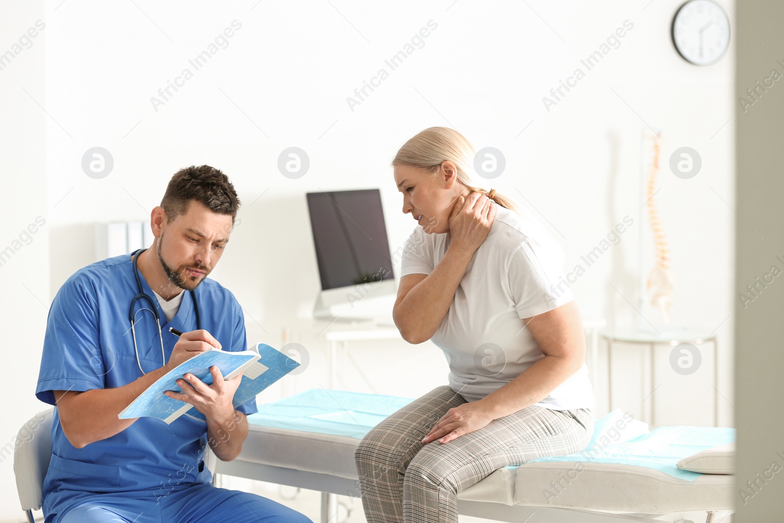 Photo of Male orthopedist examining patient with injured neck in clinic