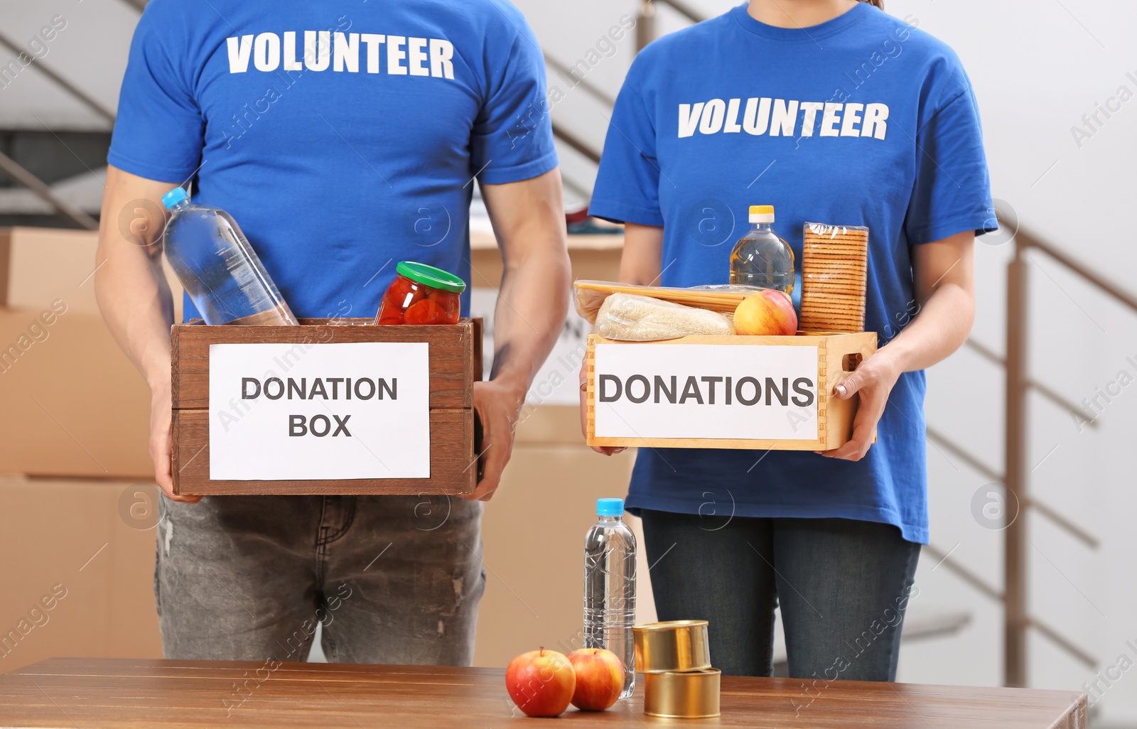 Photo of Volunteers holding donation boxes with food products indoors