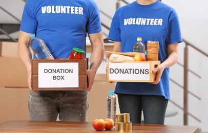 Volunteers holding donation boxes with food products indoors