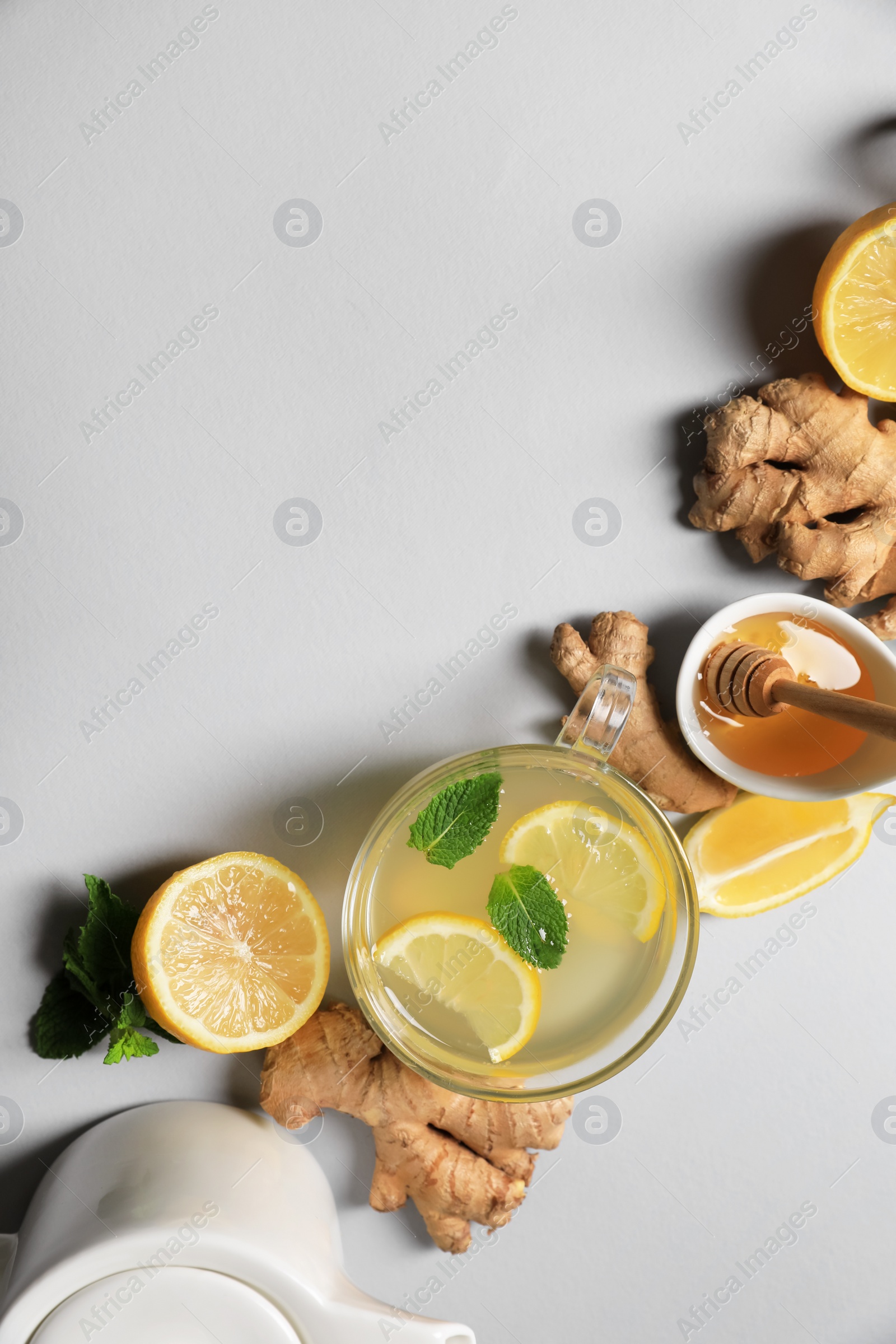 Photo of Delicious ginger tea and ingredients on light grey background, flat lay. Space for text