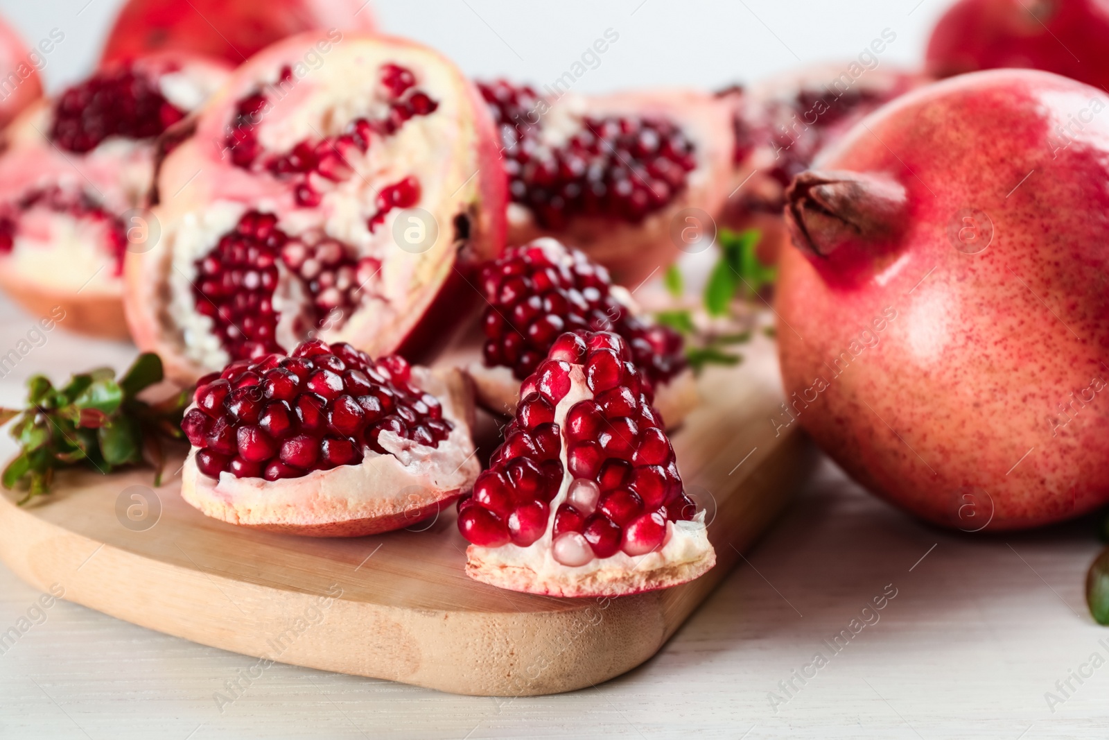 Photo of Delicious ripe pomegranates on white wooden table, closeup