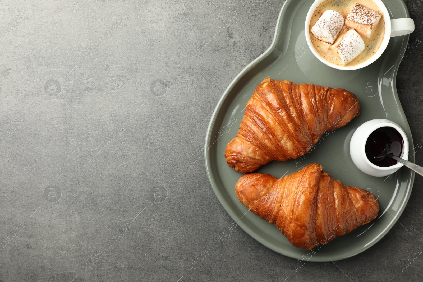 Photo of Tasty croissants served with cup of hot drink on grey textured table, top view. Space for text